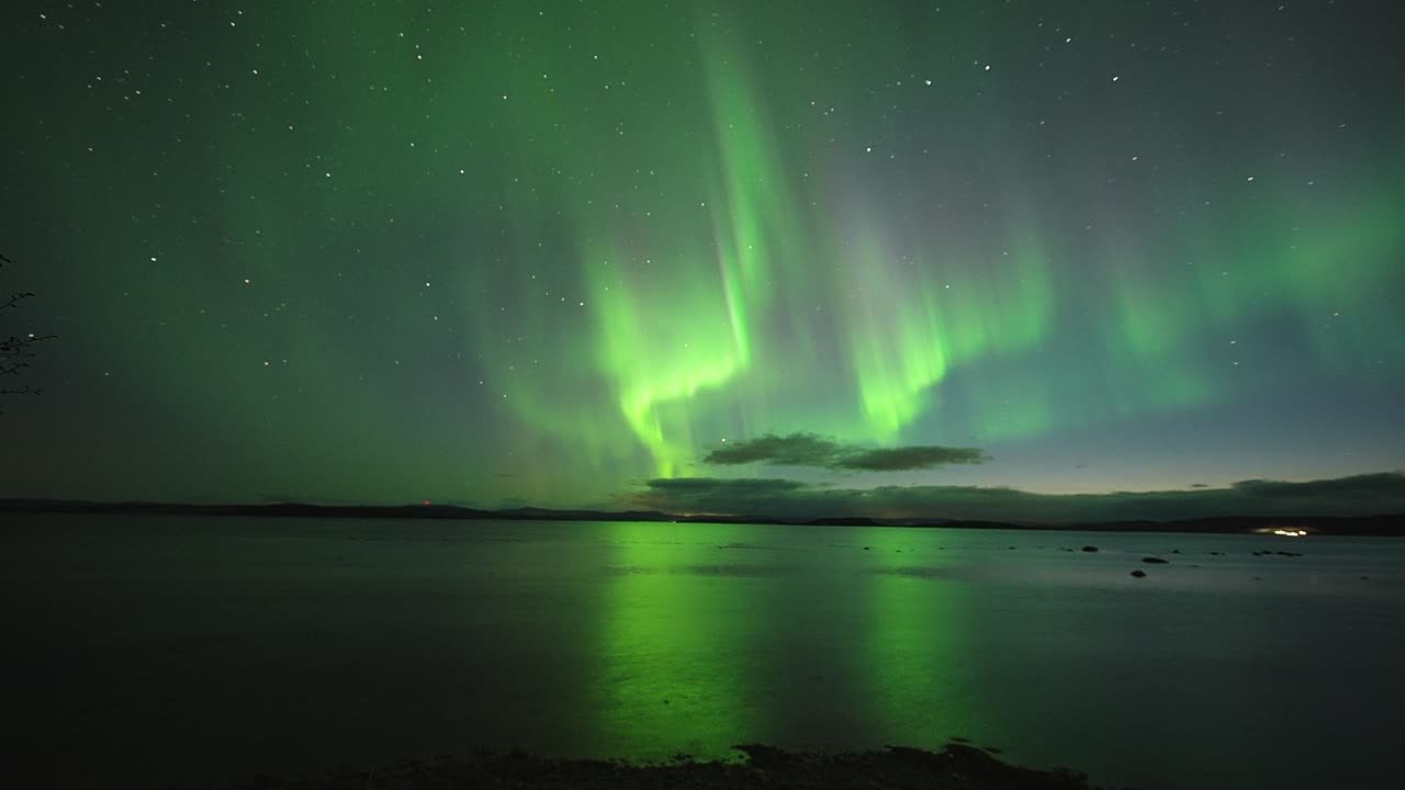 una danza hipnotizante de las luces del norte verdes y púrpuras sobre las aguas oscuras del fiordo noruego