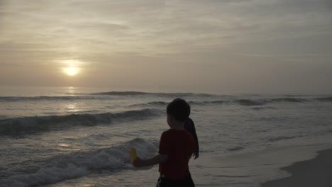 Children-playing-in-beach-waves-at-dusk