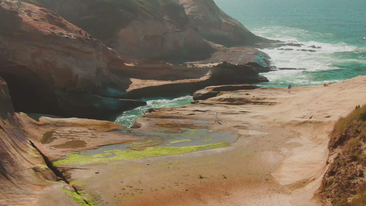 costa rocosa aérea de 4k en el océano pacífico con personas drone dolly in + jib down