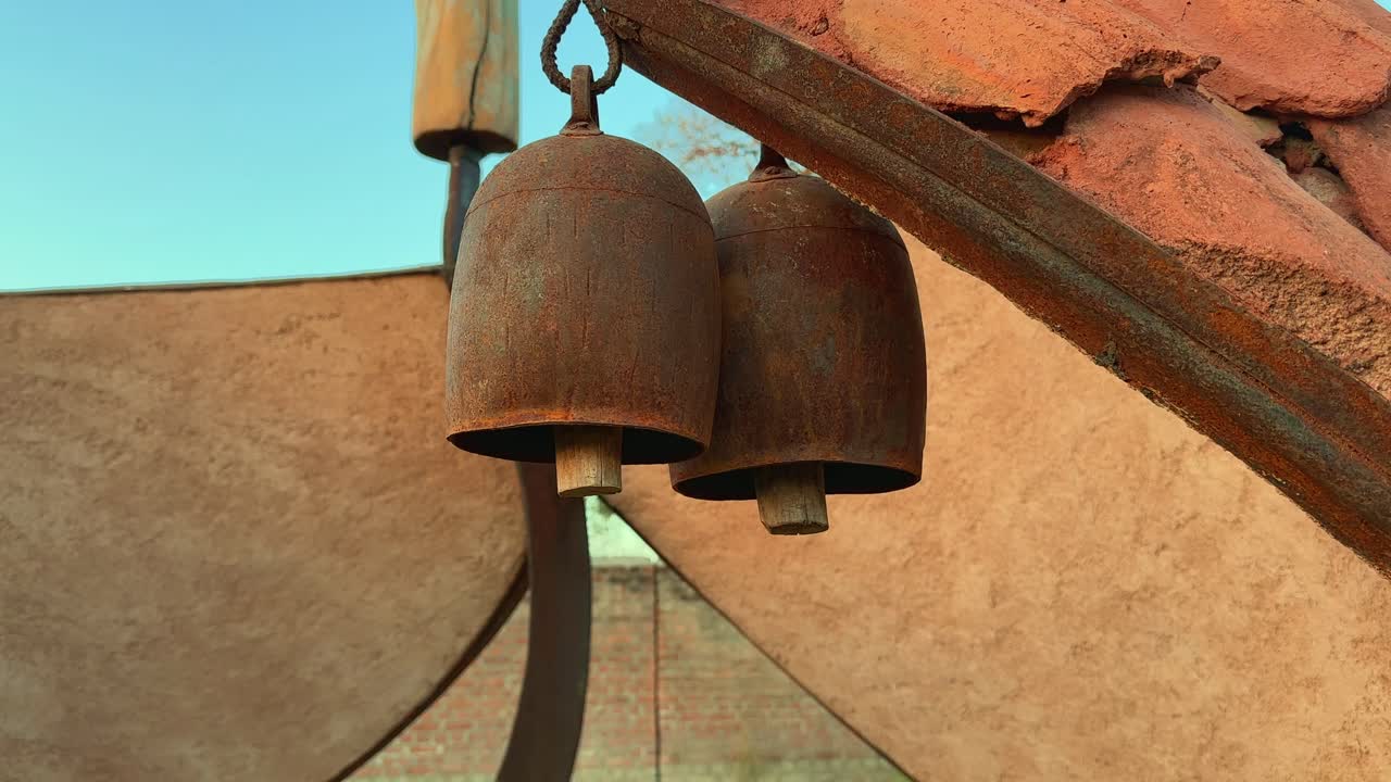 push in shot of two old rusty cattle bell hanging in the garden