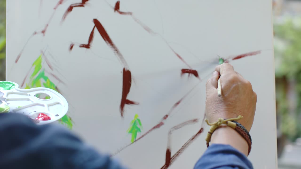 Pintor asiático mayor mezclando pintura, bloqueando relieves, añadiendo abetos para la vista en un lienzo de jardín, con espacio para texto