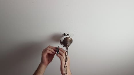 undoing an electrical tape from some wires attached to a chandelier