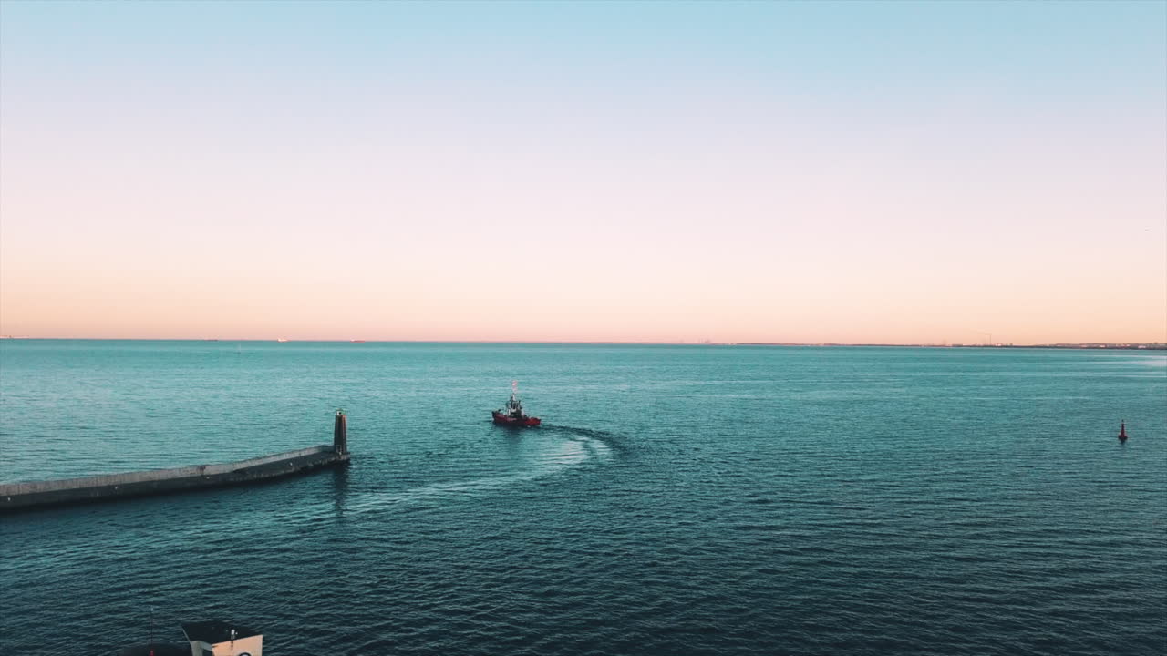 석양에 만에서 항해하는 어선 위로 날아가는 드론