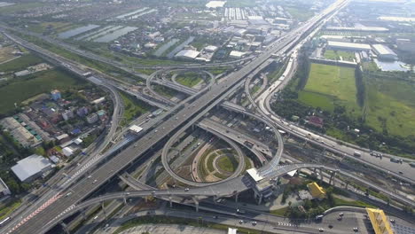 Vista-Aérea-Del-Cruce-De-Carreteras-Con-Tráfico-Urbano-Intenso-Acelerando-En-La-Carretera