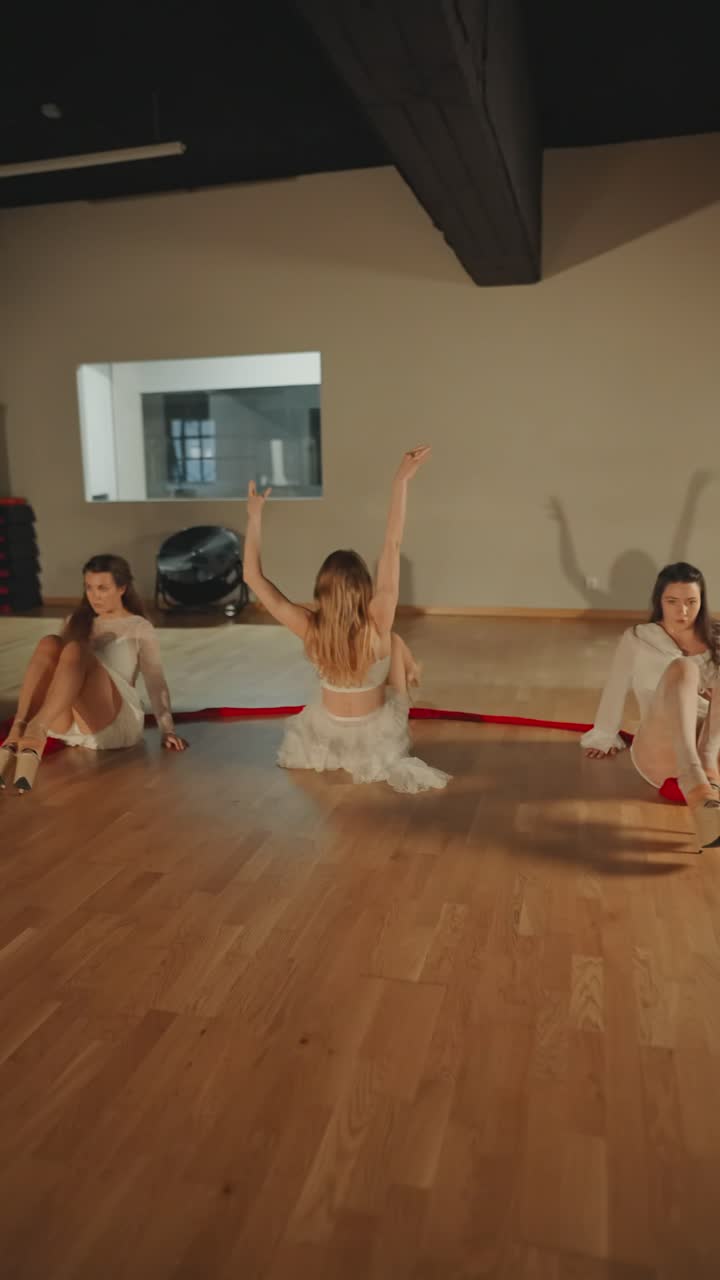 Donne in bianco che eseguono danza contemporanea con nastri rossi