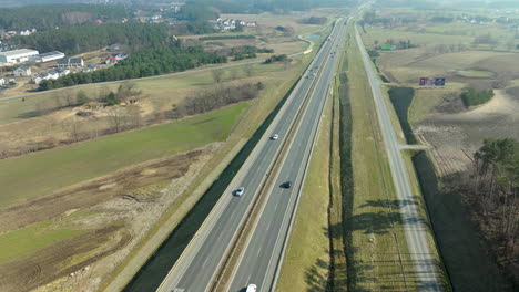 Vista-Aérea-De-Vehículos-En-Una-Carretera-Que-Atraviesa-Un-Paisaje-Rural.