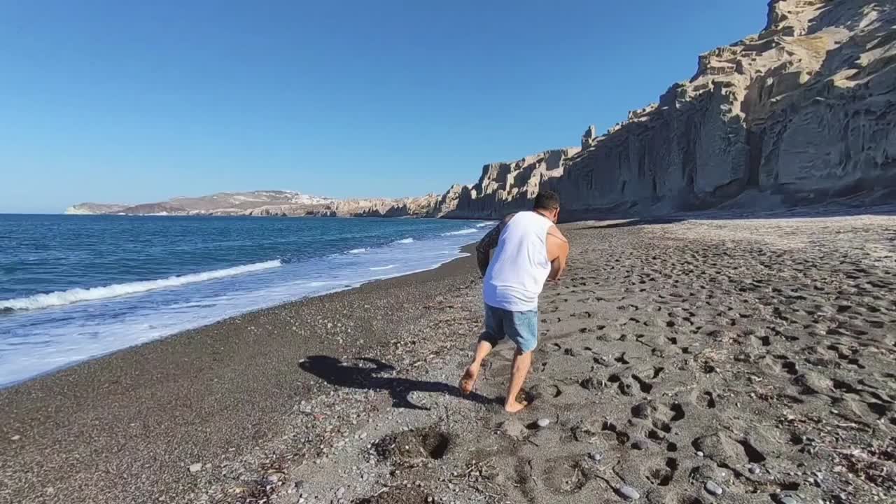 A man walking on a volcanic beach by the sea