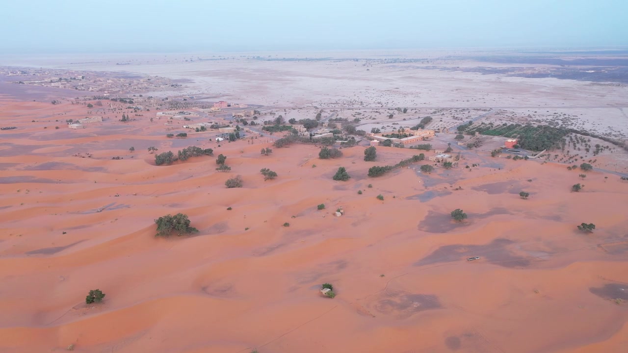 Vista aerea con drone del bordo dell'Erg Chebbi a Merzouga, dove le dune di sabbia dorata incontrano il deserto roccioso, rivelando i diversi paesaggi del Sahara marocchino.