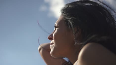 Slow-motion-of-a-pretty-brunette-hair-blowing-against-blue-sky-while-sunbathing