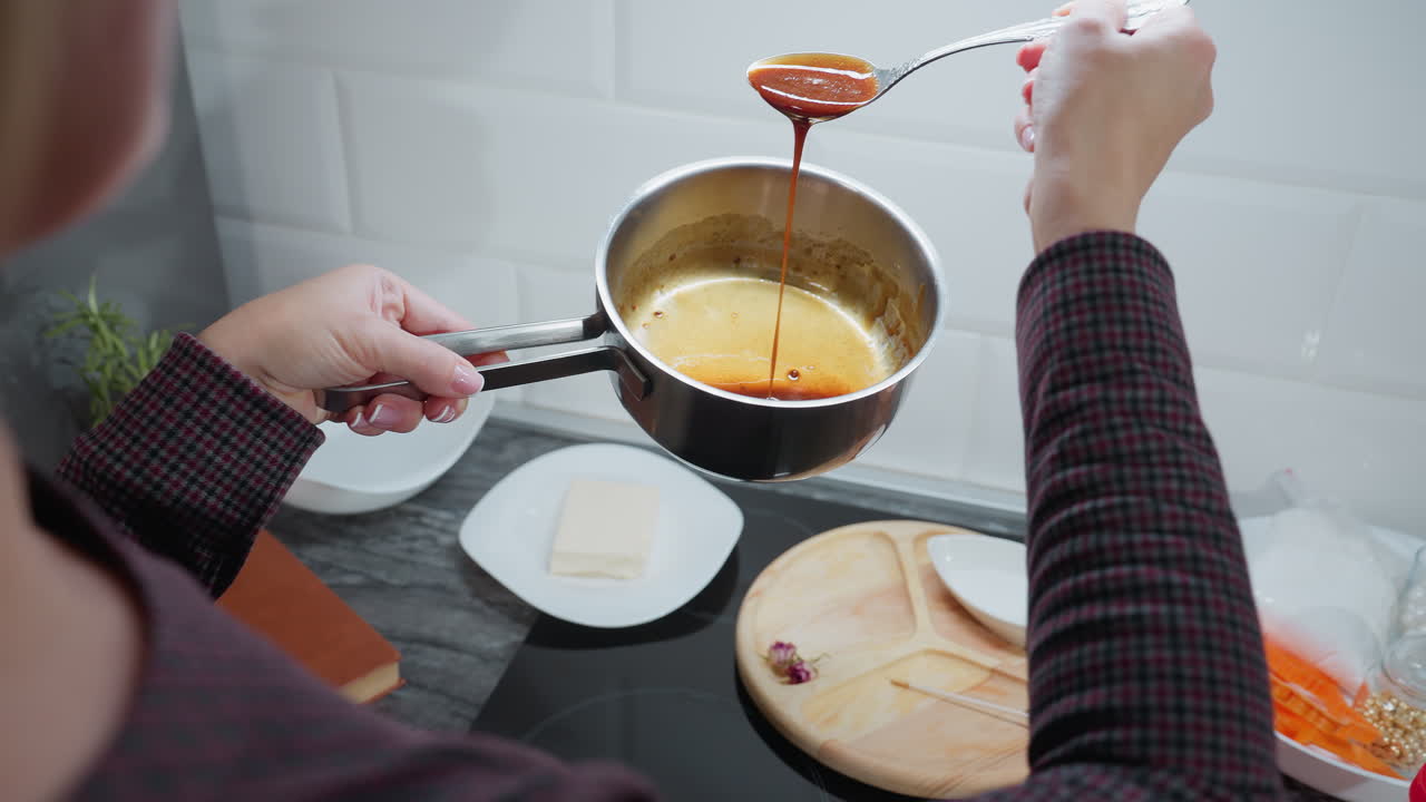 vista de atrás de una persona que vierte cuidadosamente sopa rica y roja de una cuchara en una olla en la cocina, manos con uñas cuidadosas manejan delicadamente los utensilios de cocina