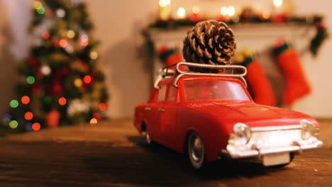 Toy-car-with-pine-cone-on-wooden-table