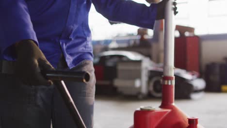 female mechanic placing oil changing equipment under the car at a car service station