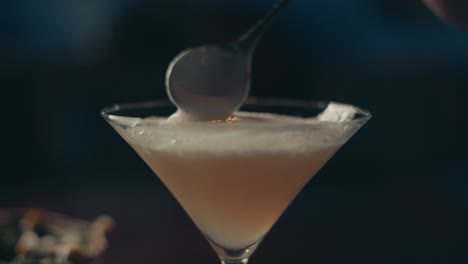 close up of classy alcoholic cocktail in glass and spoon aligning foam selective focus, slow motion