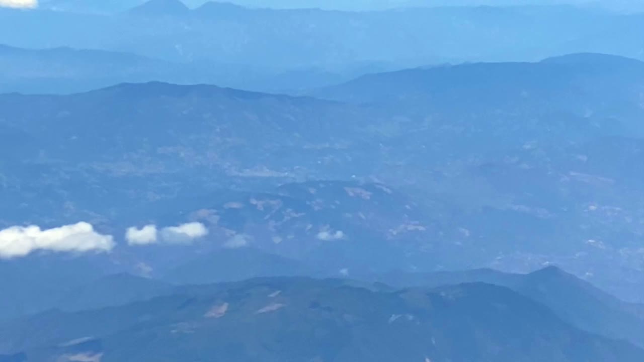 Plane window view of valleys and clouds