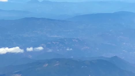 plane window view of valleys and clouds