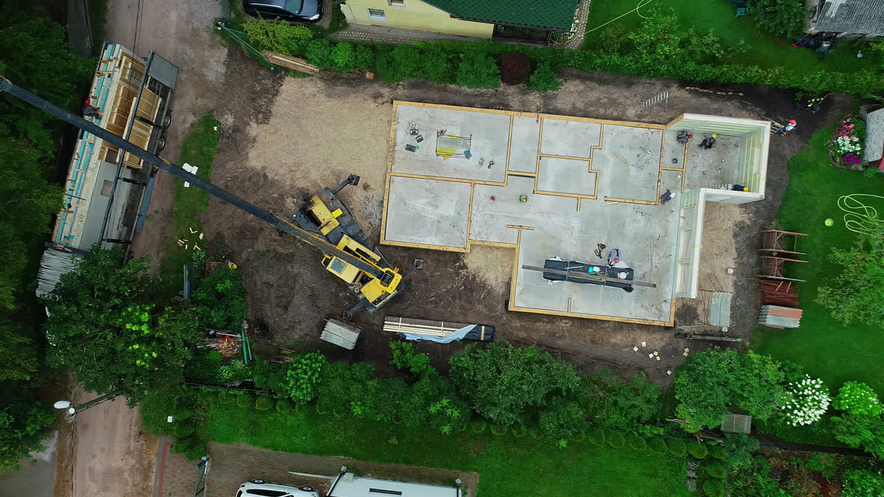 Udsigt ovenfra af en hydraulisk traktorkran, der arbejder på en byggeplads.