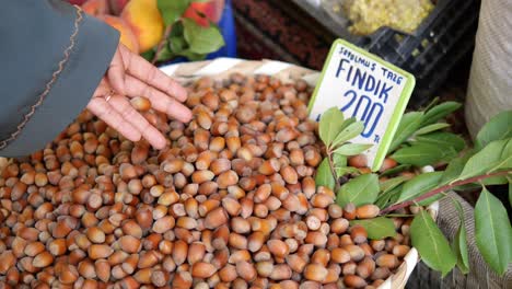 close up of a hand reaching into a basket of fresh hazelnuts