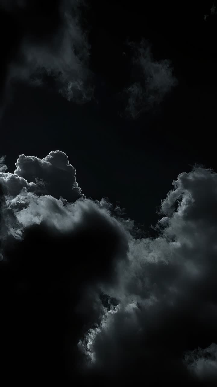 Inquadratura drammatica dal basso verso l'alto di nuvole scure e cupe con sottili punti luce, perfetta per un effetto cinematografico