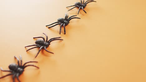 Close-up-of-multiple-spider-toys-with-copy-space-against-orange-background