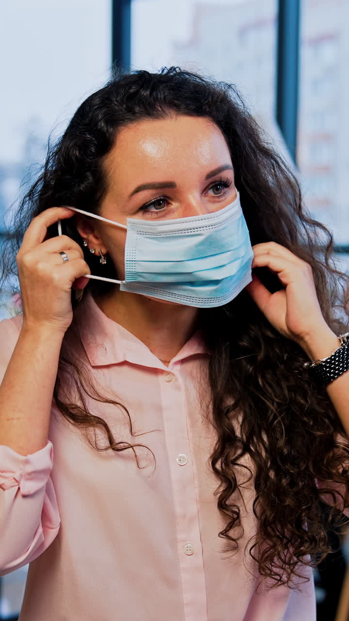mujer ajustando la máscara facial en la oficina