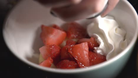 putting whipped cream on top of cut sweet strawberries