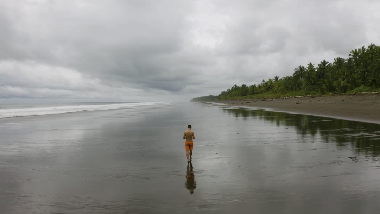 antena sigue a un joven que camina en una playa vacía, colombia