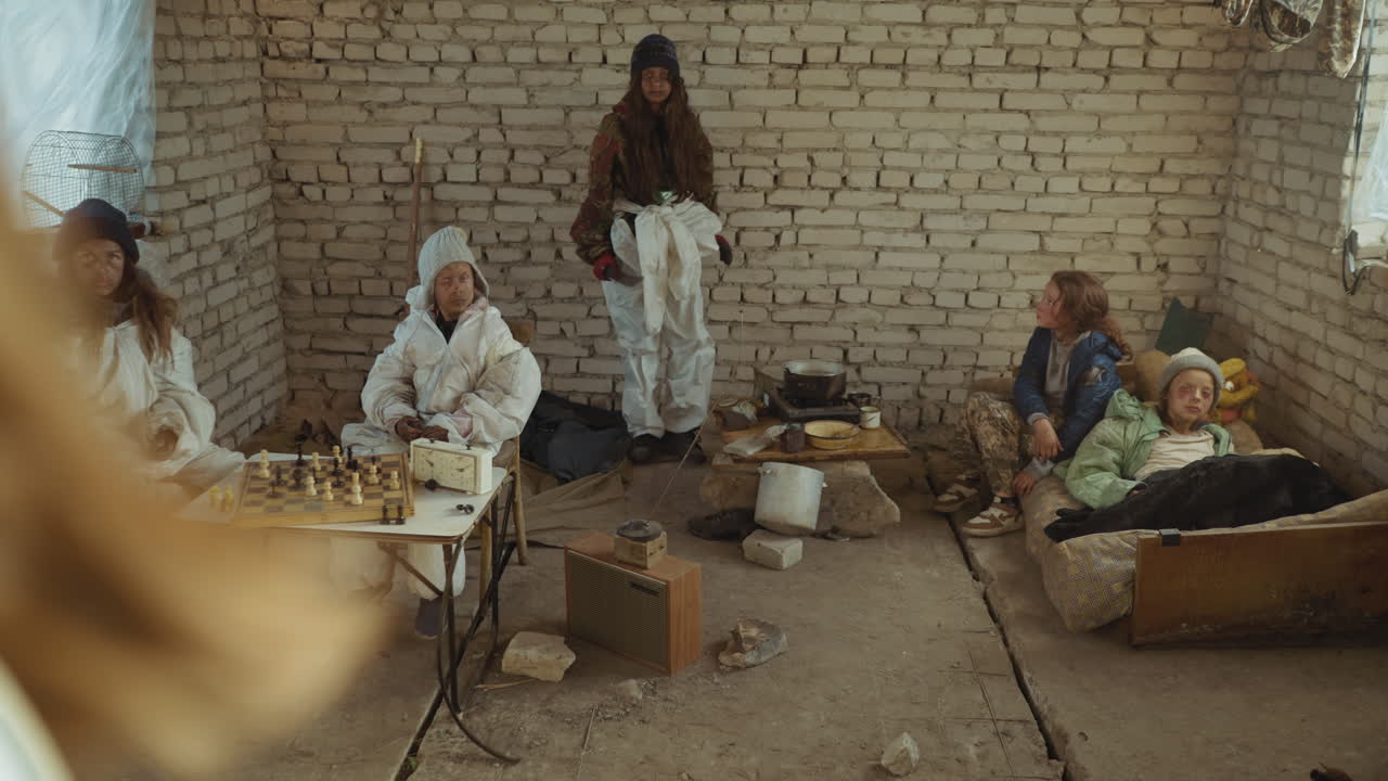 Abandoned children inside cold brick shelter turned into survival camp, faces marked with dirt as leader rises holding weapon with aggression, symbolising fear, struggle of survival after nuclear war