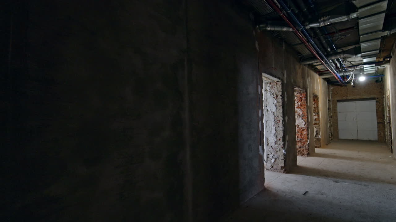 Dark corridor in the building under reconstruction. A walk along the rooms with door holes.