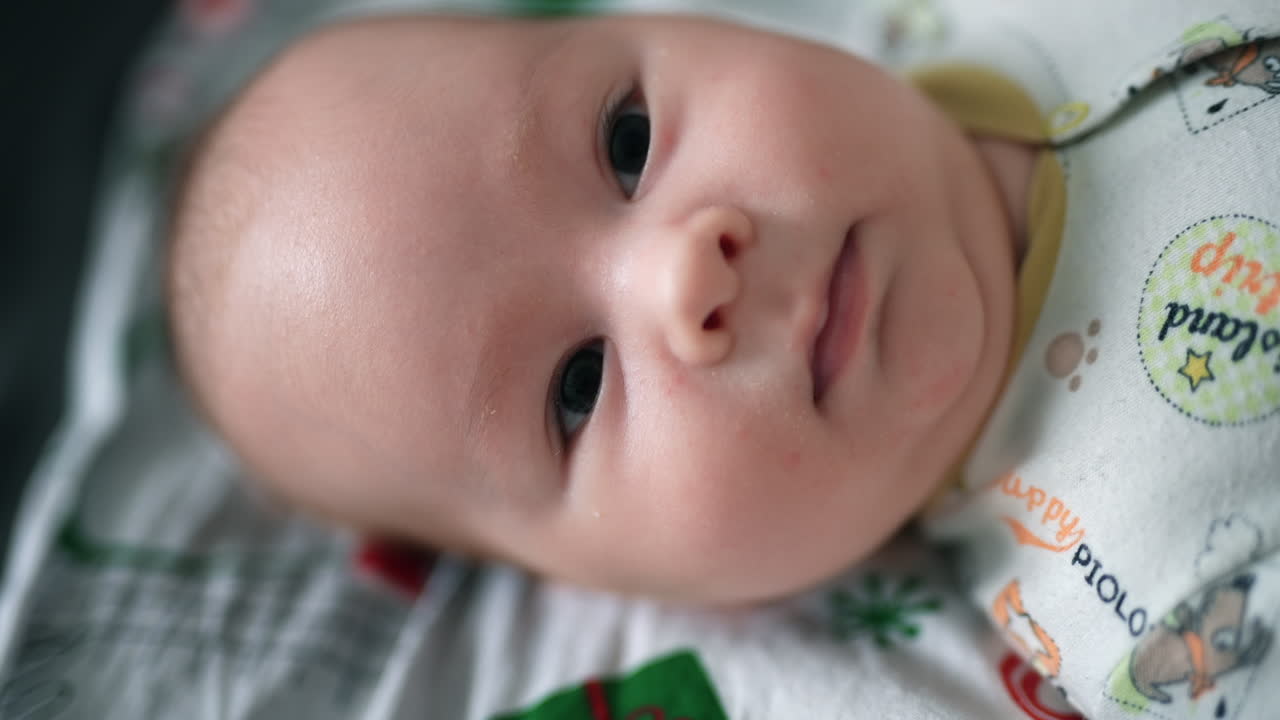 Adorable little baby with plump cheeks lying head up. Infant boy smiling sweetly to the camera. Close up.