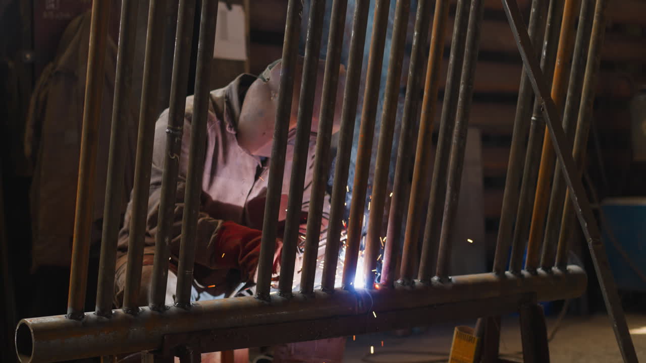 Welder in protective mask joins pipeline for mechanical room