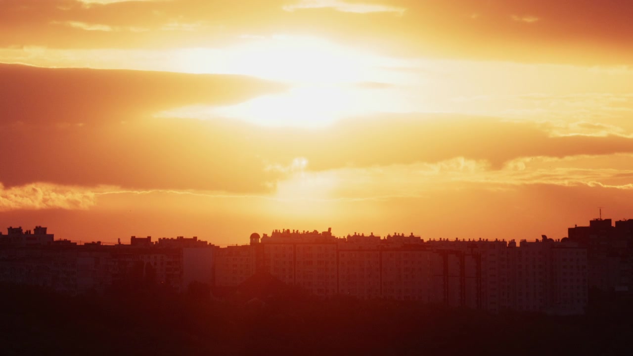 Pôr do sol dourado brilhante iluminando um horizonte de cidade moderno.