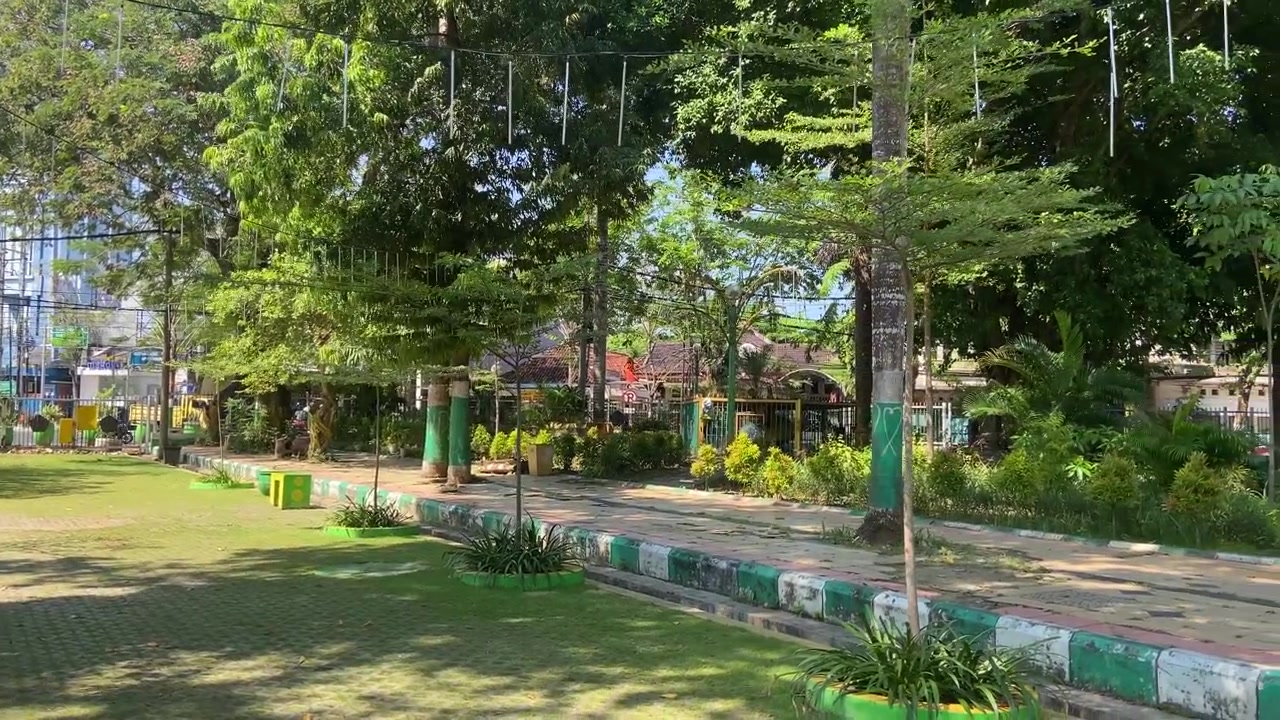 Hari Cerah di Taman Kota Hijau dengan Pepohonan dan Jalan Setapak