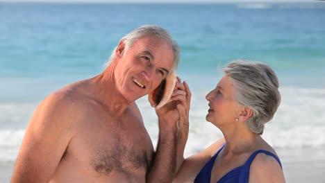 una pareja de ancianos escuchando una concha marina