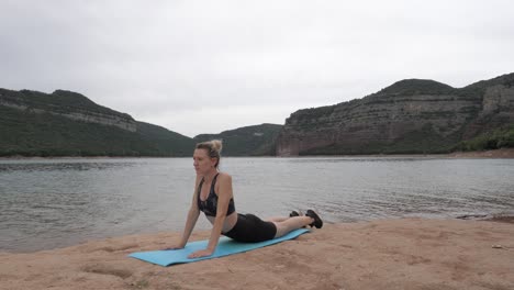 Fit-women-stretching-her-back-near-a-gorgeus-lake