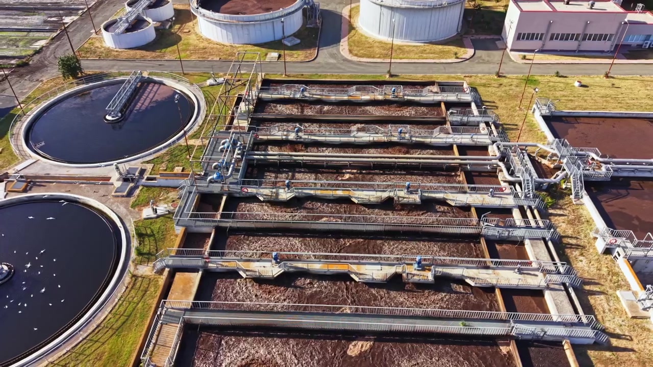 Water treatment facility working with large tanks and processing areas under clear sky on a sunny day