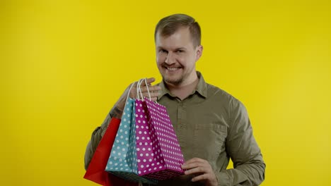 Happy-man-showing-Sale-word-inscription-from-shopping-bags,-smiling-satisfied-with-low-prices