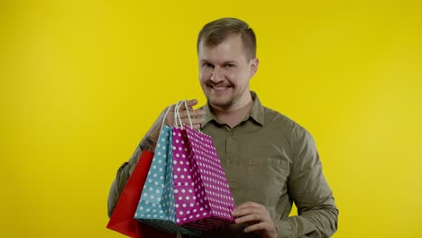 hombre feliz mostrando la inscripción de la palabra de venta de las bolsas de compras, sonriendo satisfecho con los precios bajos