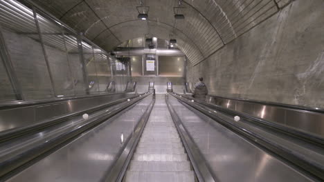 pov of a person going up by an escalator and looking down inside nationaltheatret station in oslo, norway during pandemic