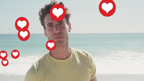 animation of social media heart icons over portrait of smiling man on beach
