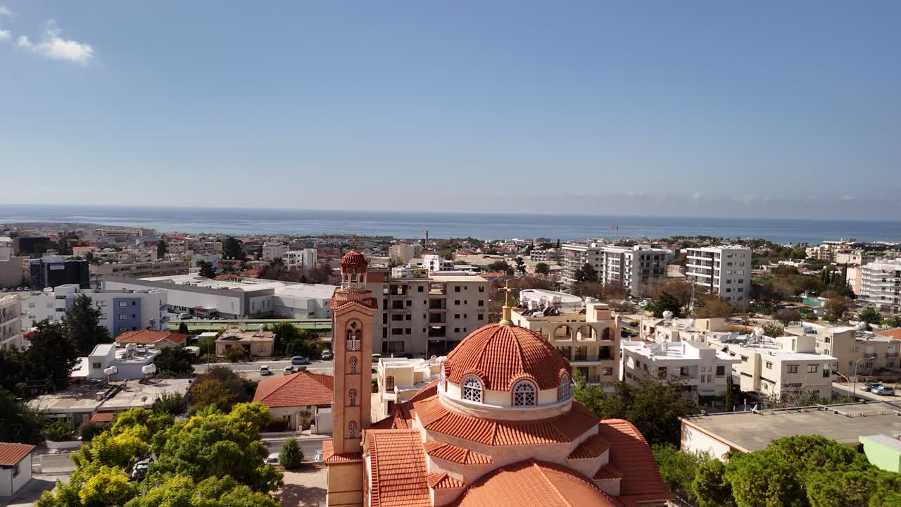 Stunning aerial view of a coastal town featuring a historic church, lush greenery, and a serene sea. Perfect day with clear skies and vibrant surroundings