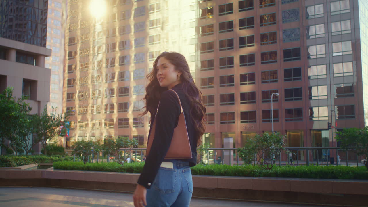 una chica encantadora tocando el peinado caminando por la calle. una mujer asiática disfruta relajándose en megapolis.