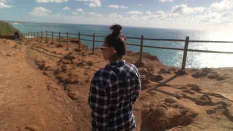 mujer caminando por el sendero de los acantilados costeros
