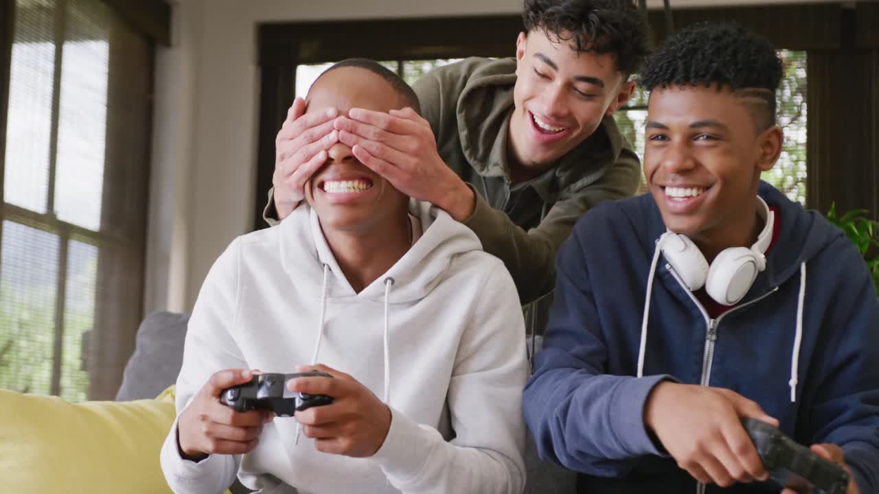Happy diverse male teenage friends playing video games at home, slow motion