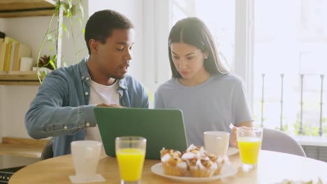 couple having breakfast and using laptop at home