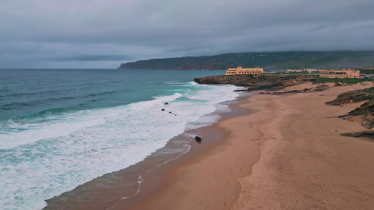 Sea foaming sandy coast under cloudy gray sky drone view. Amazing ocean waves