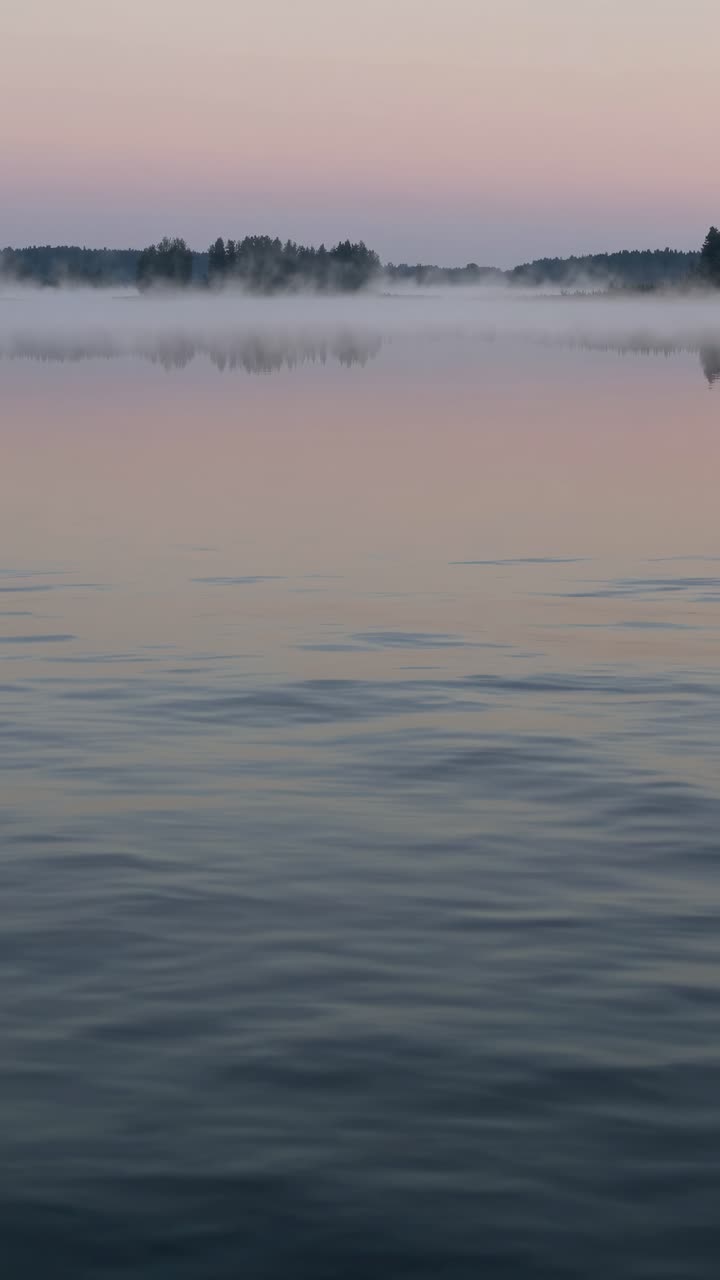 Serene lake at dawn with mist, captured from a low angle. Soft pastel hues create a tranquil