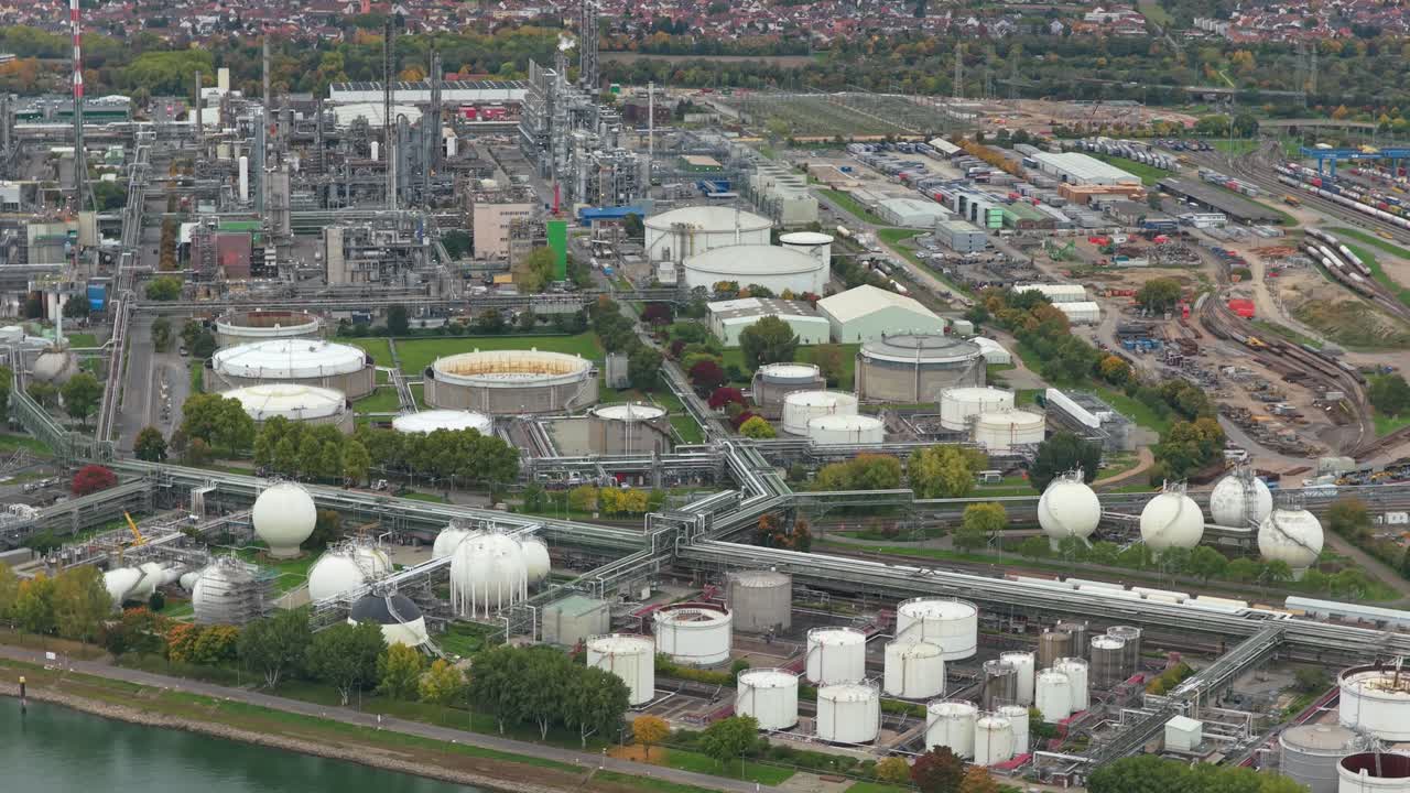 Extensive aerial shot of a large chemical plant or oil refinery with storage tanks, pipelines, and distillation towers located by a river