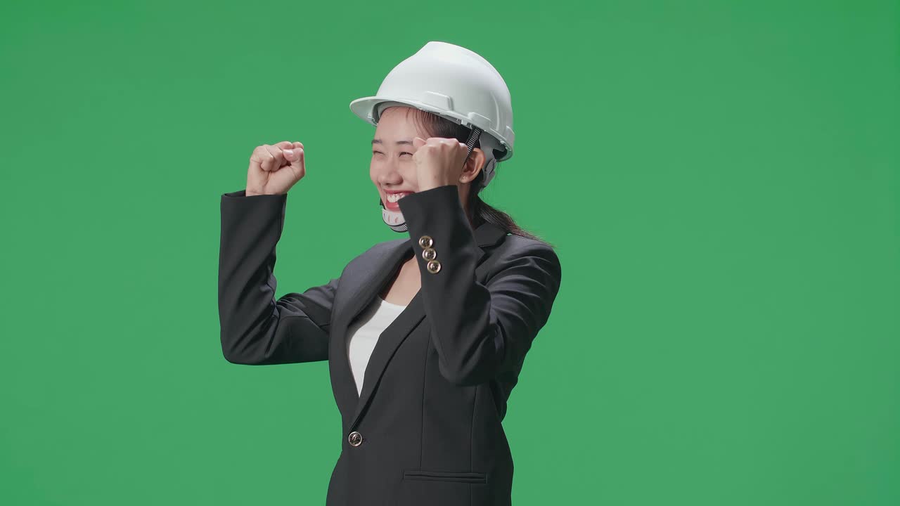 Side View Of Happy Asian Female Engineer With Safety Helmet Celebrating In The Green Screen Studio