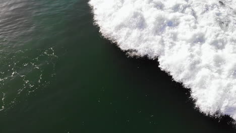 Drone-flyover-pullback-of-crashing-wave,-no-surfers,-Pacific-Ocean-at-Huntington-Beach,-California,-roiling-surf,-4k,-aerial,-overhead,-white-water-foam