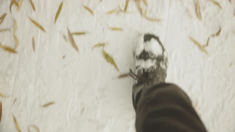 man walking on snow-covered park during winter. pov